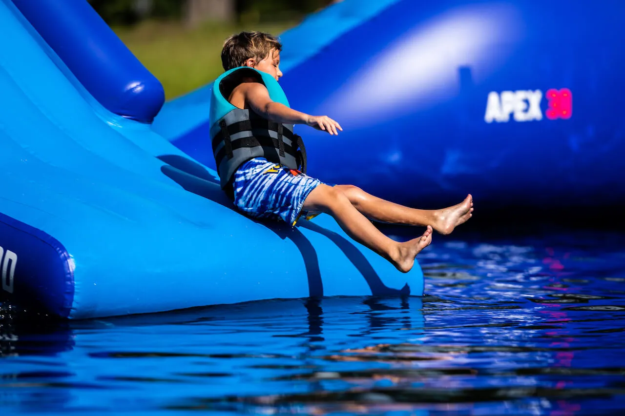 Campers on floating obstacle course aqua park at summer camp